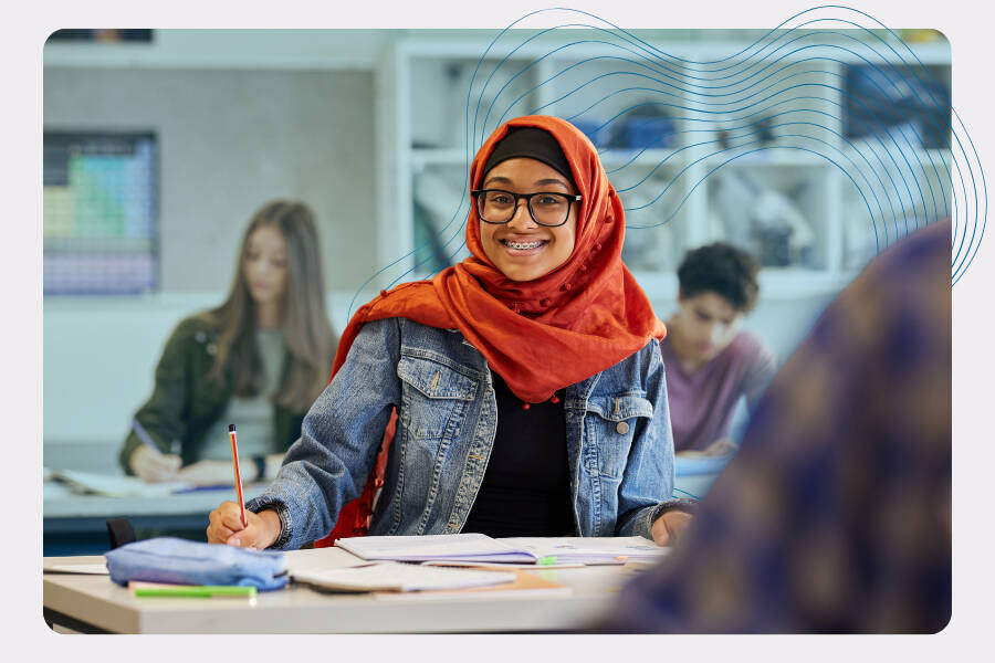 Student smiling while working at a desk in a classroom.